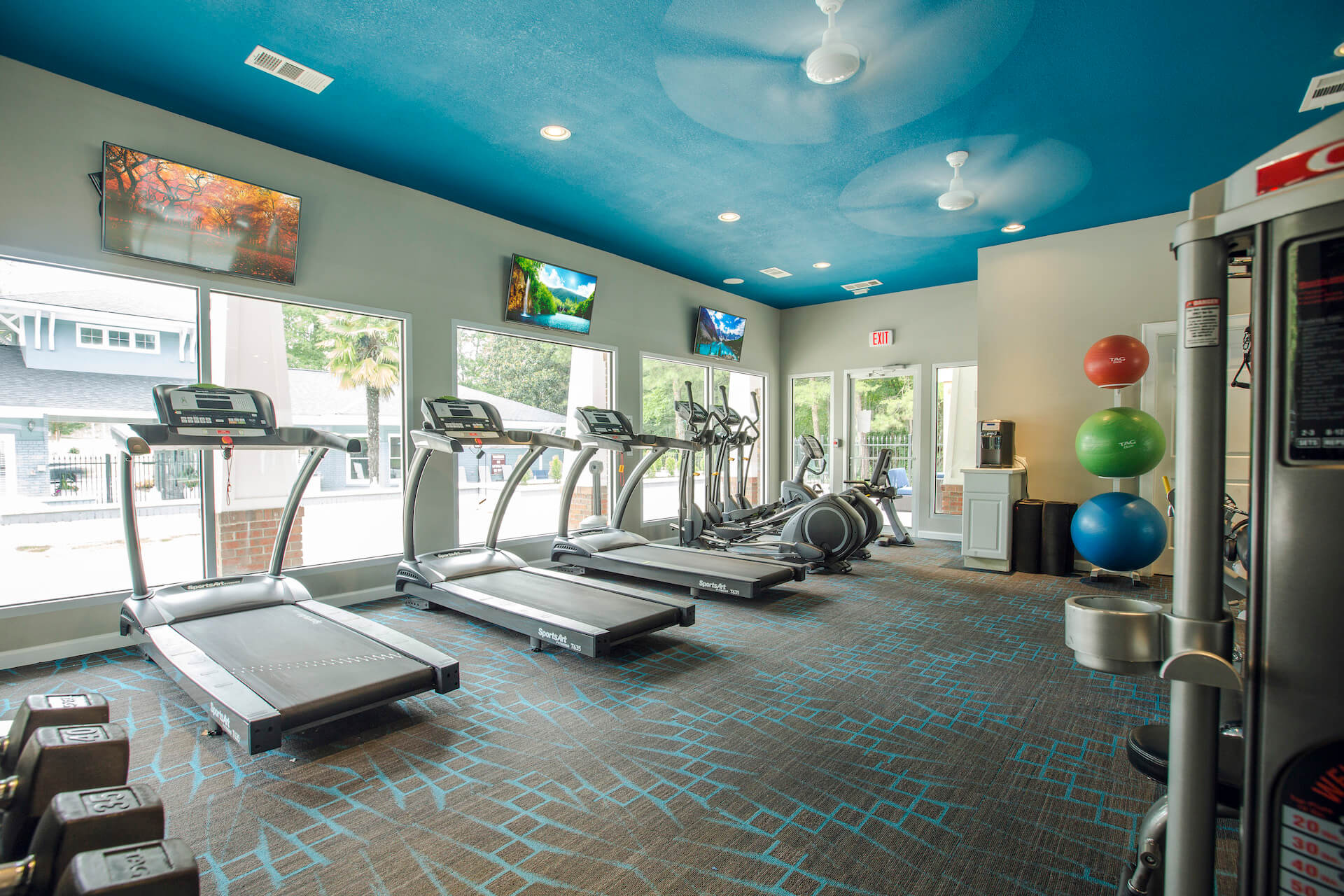 state-of-the-art fitness center showing treadmills, stationary bikes and wall-mounted TVs