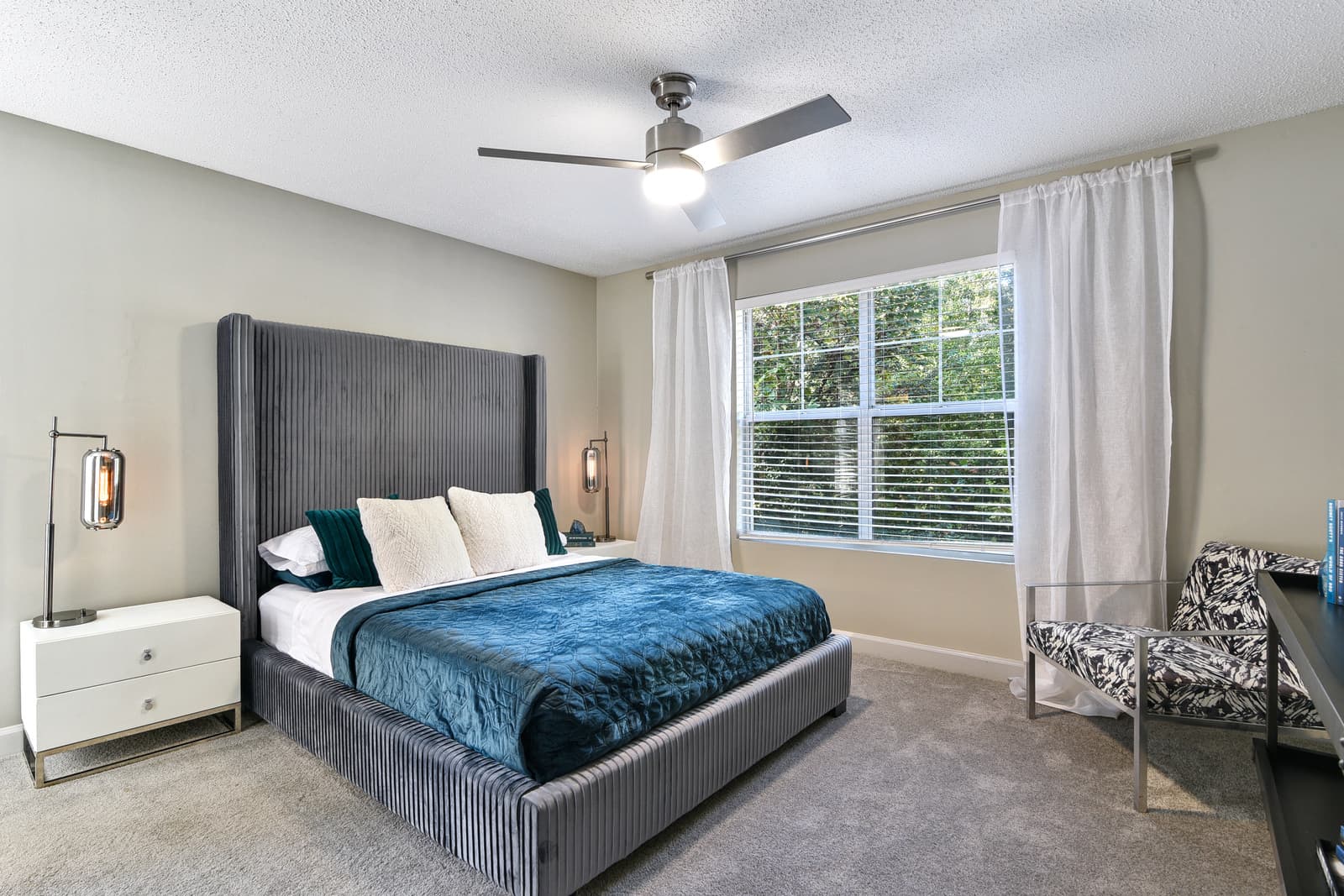 fully furnished bedroom with modern ceiling fan and large window